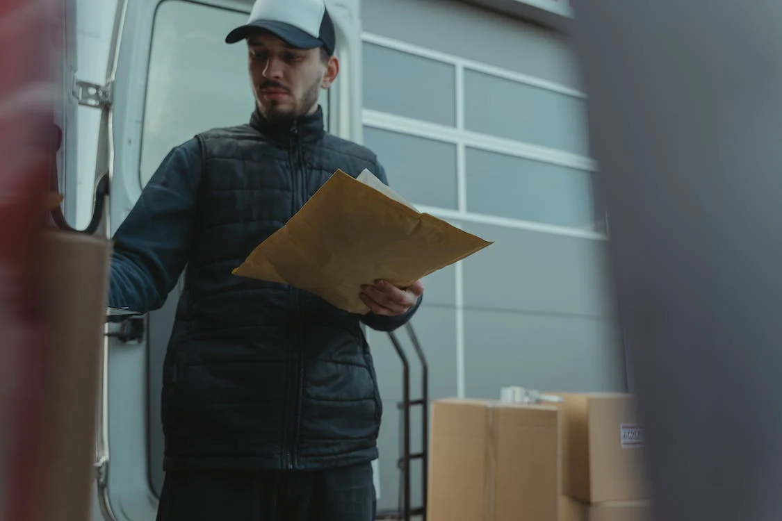  A man carefully inspecting items on store shelves, holding a commercial invoice