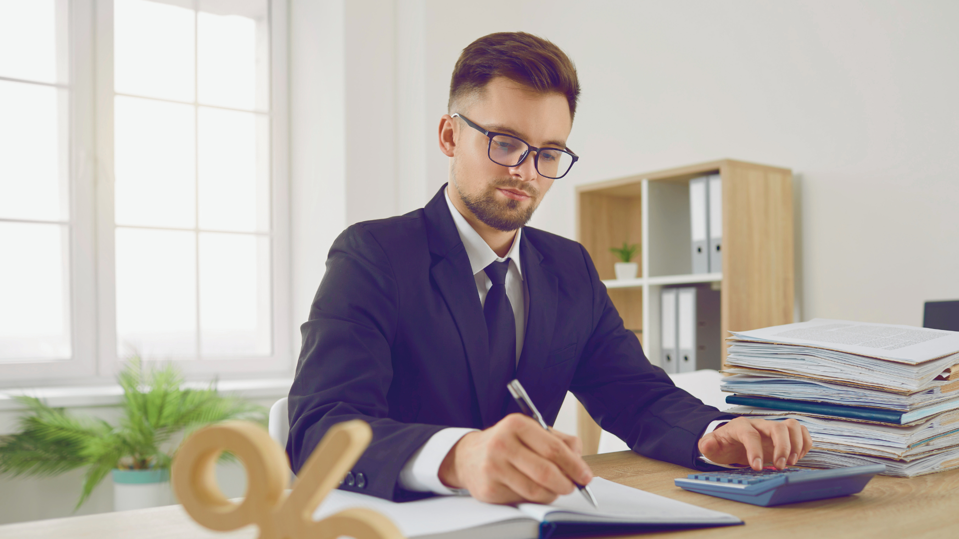 A man in a suit writing in a notebook